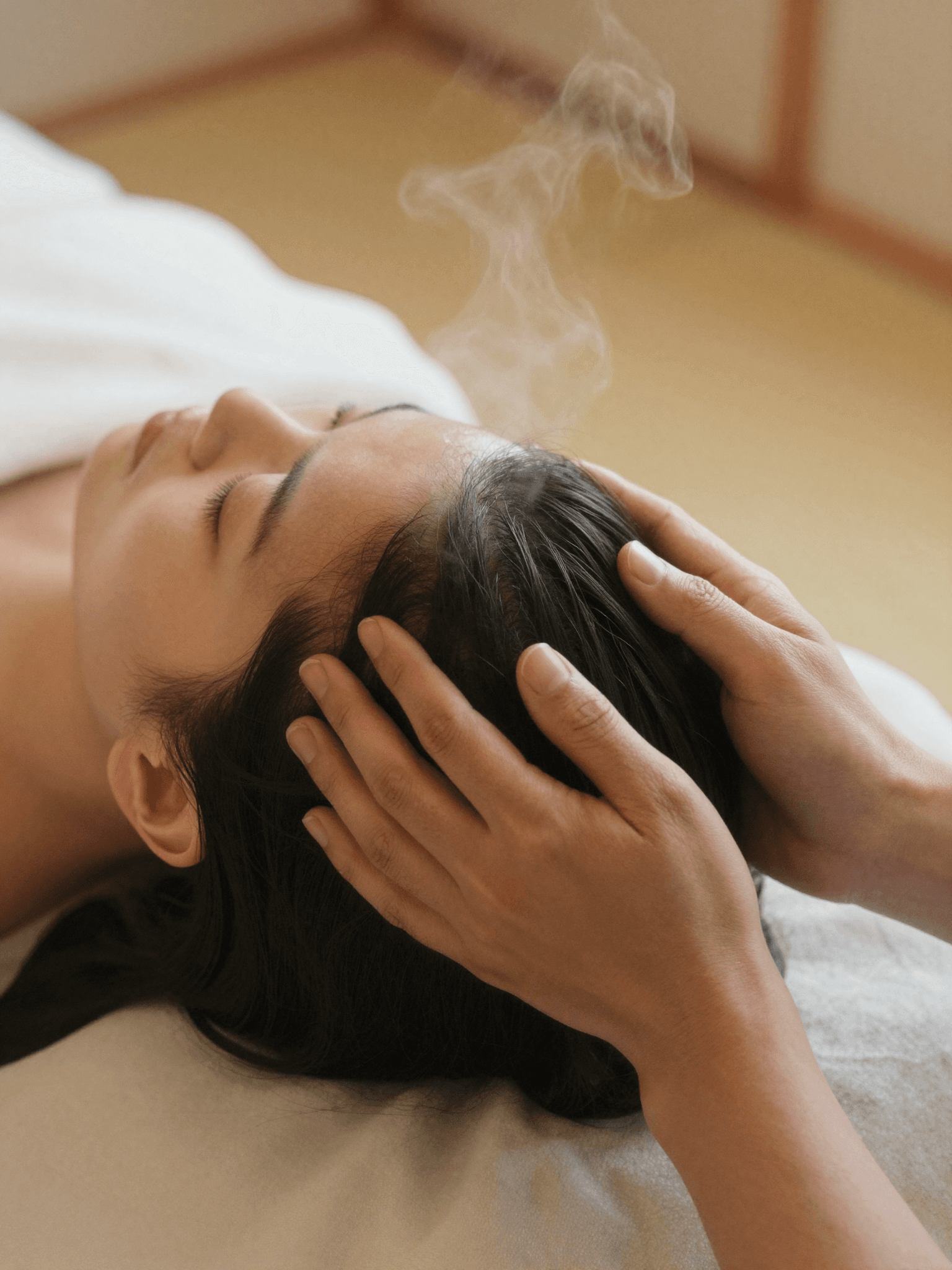 A therapist massages a relaxed client’s scalp during the signature Japanese head spa ritual, steam rising softly